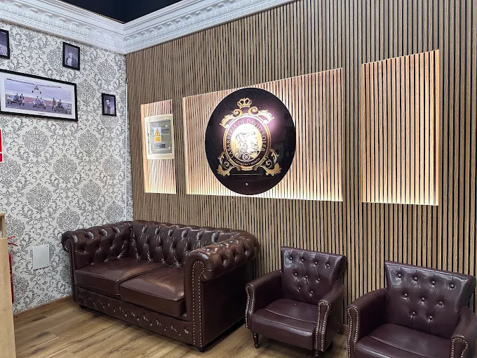 Sofá de cuero y emblema de la barbería sobre una pared de madera